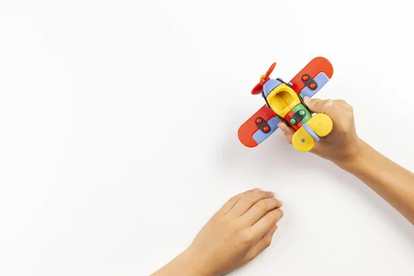 Avion jouet coloré dans les mains des enfants sur fond blanc. Vue du dessus — Photo