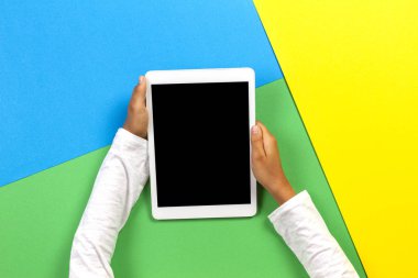 Sarı, mavi ve yeşil arka planda tablet bilgisayar ile Çocuk eller