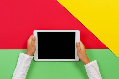 Kırmızı, sarı ve yeşil arka planda tablet bilgisayar ile Çocuk eller