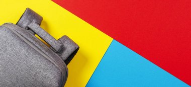 Gri sırt çantasının sarı, mavi ve kırmızı arka planda üst görünümü