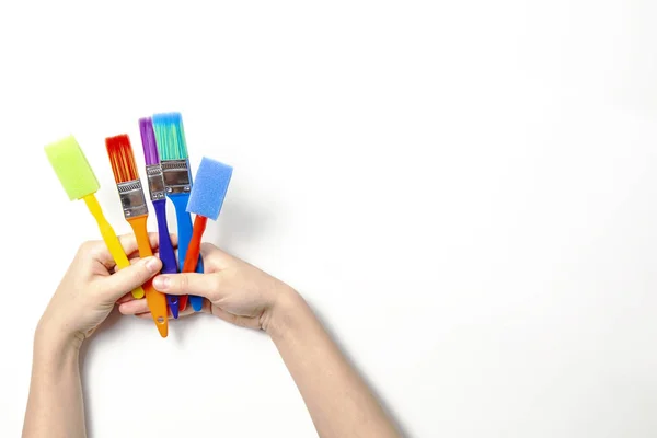 Дитячі руки тримають барвисті пензлі на білому тлі — стокове фото