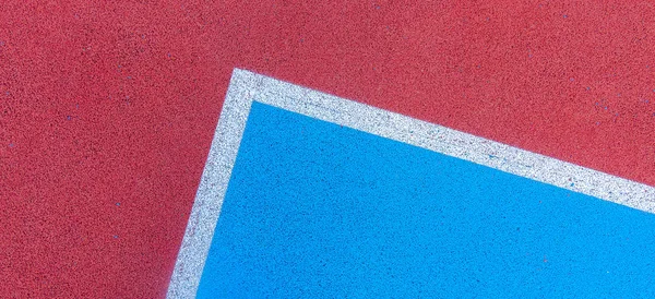 Fondo colorido de la cancha deportiva. Vista superior al suelo de goma de campo rojo y azul con líneas blancas al aire libre —  Fotos de Stock