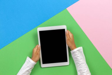 Pastel pembe, mavi ve yeşil arka plan üzerinde tablet bilgisayar ile Çocuk eller