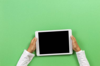 Açık yeşil arka plan üzerinde tablet bilgisayar ile Çocuk eller. Üstte görüntü