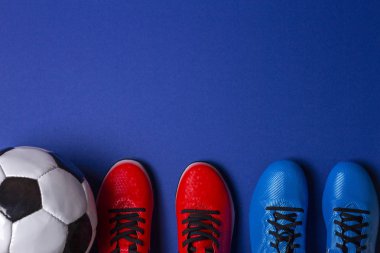 Futbol topu ve futbol futbol iki çift üstten görünüm spor ayakkabıları mavi zemin üzerine