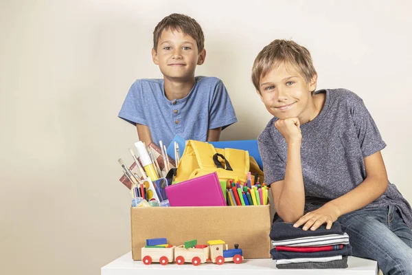 Donation concept. Kids holding donate box with books and school supplies, clothes and toys