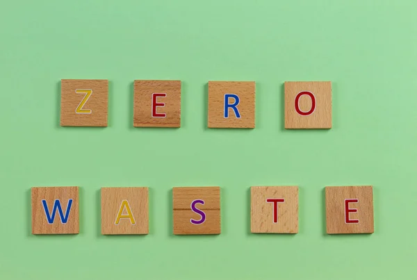 Das Wort Zero Waste, geschrieben mit hölzernen Buchstabenkacheln vor hellgrünem Hintergrund. Ansicht von oben — Stockfoto