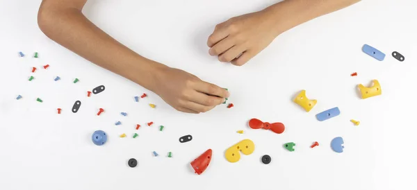 Les mains des enfants jouant avec les pièces colorées en plastique du constructeur. Vue du dessus — Photo