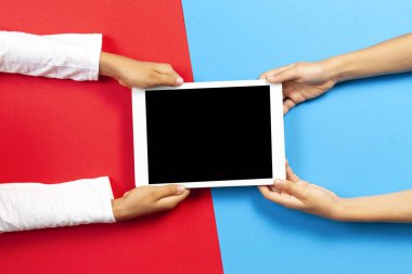 Tablet bilgisayarı kırmızı ve açık mavi arka plan üzerinde tutan çocuklar