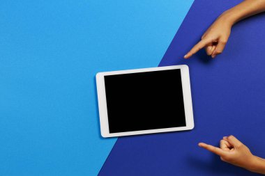 Mavi arka plandaki boş tablet bilgisayara parmak laişaret eden çocuk elleri
