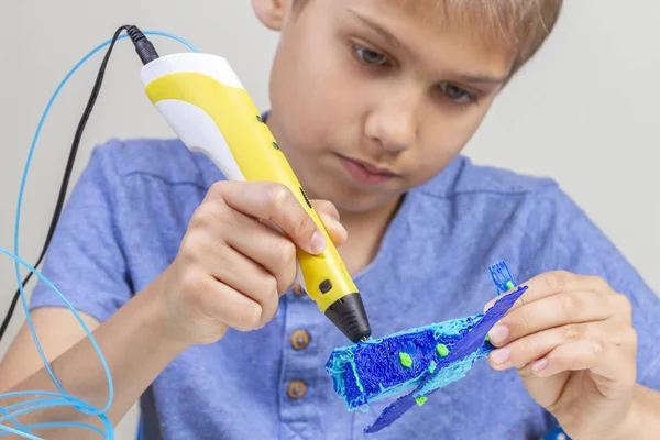 Mãos de menino criando com caneta 3d plano azul — Fotografia de Stock