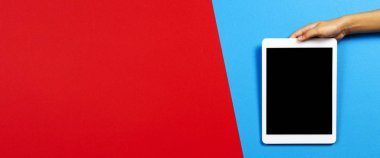 Kırmızı ve açık mavi arkaplanda tablet bilgisayarlı çocuk eli