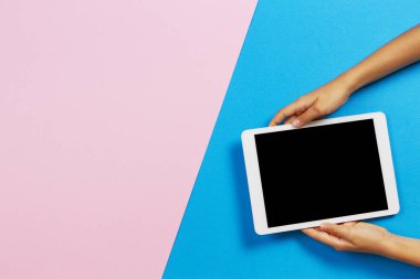 Pastel pembe ve mavi arka plan üzerinde tablet bilgisayar ile Çocuk eller