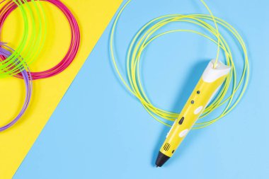 mavi ve sarı arka plan üzerinde renkli plastik filaman ile 3D kalem.