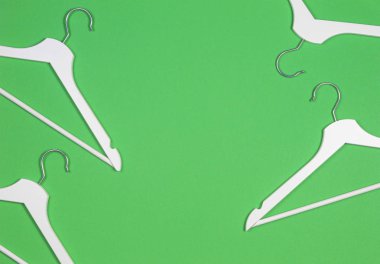 Pastel yeşil arka planda beyaz ahşap askılar. Alışveriş, satış, promosyon, sosyal medya, yeni sezon konsepti