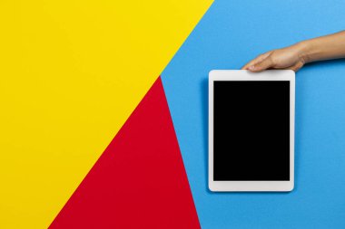 Sarı, kırmızı ve açık mavi arka plan üzerinde tablet bilgisayar ile Çocuk el