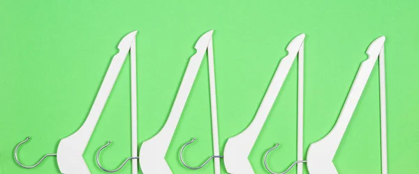 Cabides de madeira brancos dispostos em fundo verde pastel. Compras, venda, promoção, mídia social, conceito de nova temporada — Fotografia de Stock