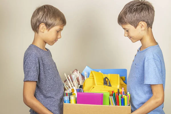 Donation concept. Kids holding donate box with books and school supplies