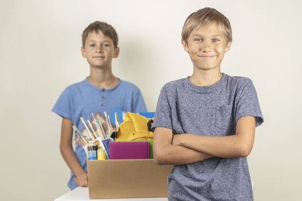 Concepto de donación. Niños felices de ayudar a otros. Niños con caja de donaciones con libros y útiles escolares —  Fotos de Stock