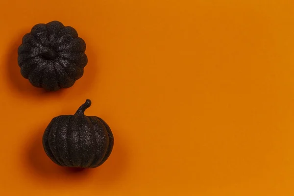 Fondo mínimo de Halloween. Calabazas decorativas negras brillantes sobre fondo naranja. Vista superior — Foto de Stock