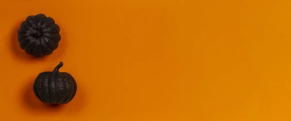 Fondo mínimo de Halloween. Calabazas decorativas negras brillantes sobre fondo naranja. Vista superior — Foto de Stock