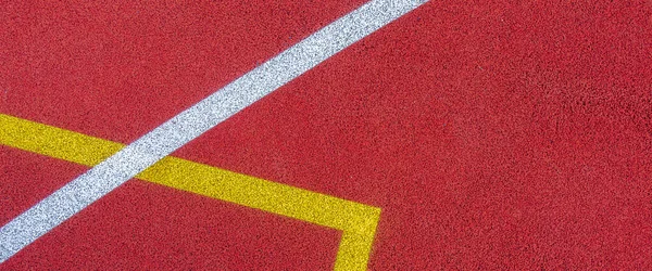 Colorful sports court background. Top view to red field rubber ground with white and yellow lines outdoors