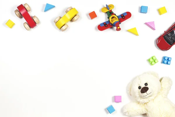 幼儿玩具框架与玩具汽车，玩具熊，五彩斑斓的平面，木制砖白色背景。 俯瞰，平铺 — 图库照片