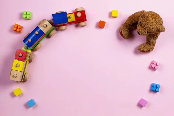 Bebê crianças brinquedos fundo. Urso de pelúcia, trem de madeira e blocos coloridos em fundo rosa claro — Fotografia de Stock