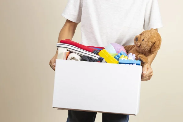 Donatie concept. Kinderen handen houden doneren doos met boeken, kleding en speelgoed — Stockfoto