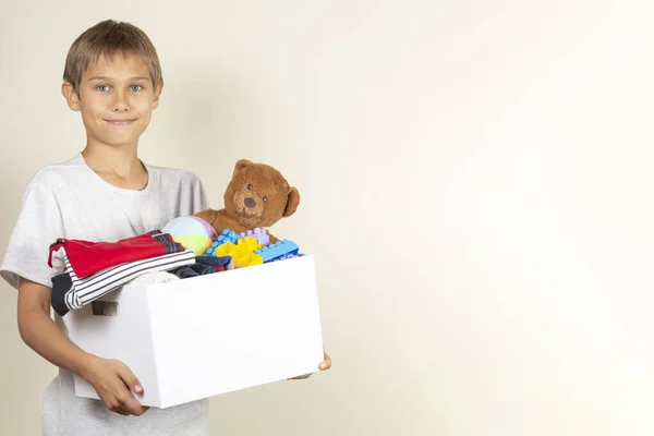 Donation concept. Kid holding donate box with books, clothes and toys