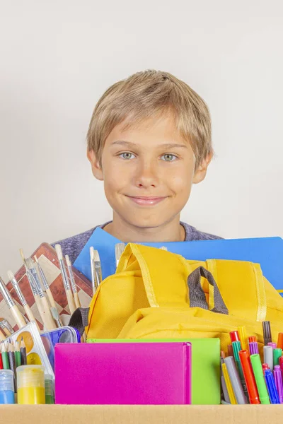 Conceito de doação. Kid holding doar caixa com livros, lápis e material escolar — Fotografia de Stock