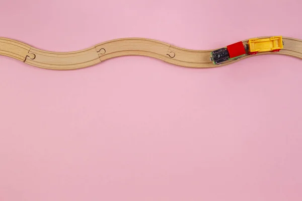 Trem de brinquedo e trilhos de madeira no fundo de cor rosa pastel — Fotografia de Stock