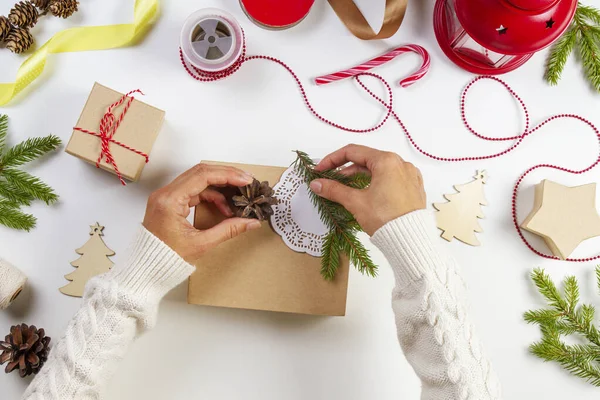 Christmas present gift wrapping. Top view to womans hands packing Christmas presents on white table