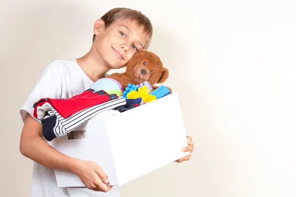 Concepto de donación. Niño sosteniendo donar caja con libros, ropa y juguetes —  Fotos de Stock