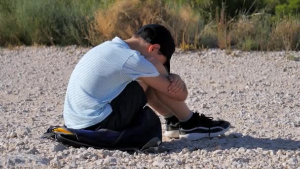 Trauriger unglücklicher Junge, der allein auf seinen Knien im Freien sitzt. Kinderdepressionen, Missbrauch, Kinderprobleme — Stockvideo