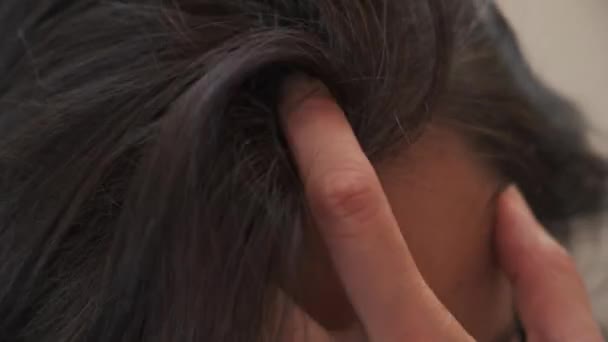 Middelbare leeftijd vrouw aanraken van haar donkere haar met grijs haar aan de wortels van het haar — Stockvideo