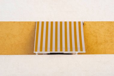 Çizgili gölgeli pencere beyaz ve sarı duvarlı güneş koruması. En küçük arkaplan