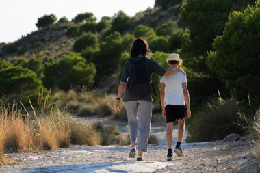 Anne ve oğlu güneşli bir günde ormanda birlikte yürüyorlar.