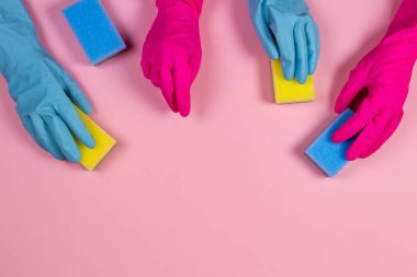 Pembe ve açık mavi kauçuk eldivenli pembe arka planda süngerli kadınlar