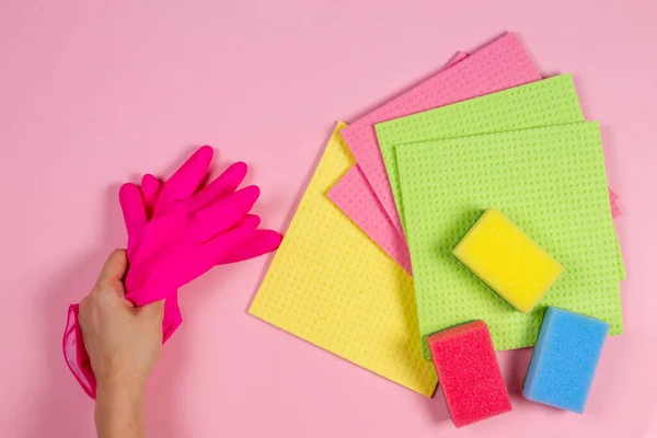 Fondo de limpieza del hogar. Guantes de goma de mano de mujer, muchas esponjas sobre fondo rosa — Foto de Stock