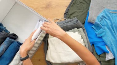 Giysilerin dikey depolanması, Marie Kondo 'nun toparlanma yöntemi, oda temizliği konsepti. Kadın elleri temizlik yapıyor ve giysileri sepete koyuyor. Üst alt görünüm