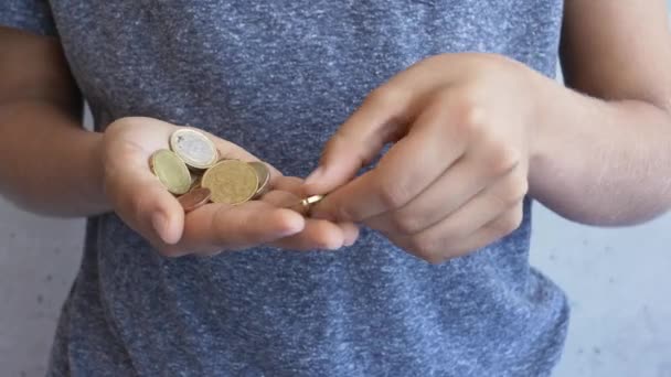Pojken räknar euromynt i sina händer. Grabben sparar pengar. Barnet räknar sina besparingar — Stockvideo