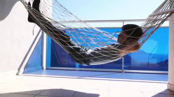 Entertainment thuis tijdens quarantaine. Kid leggen en ontspannen in hangmat opknoping op balkon van appartement. Kind swingend en dromend, denkend — Stockvideo