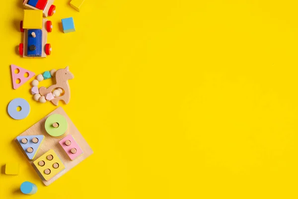 Babyspielzeug Hintergrund. Holzzug, pädagogisches Stapeln von Puzzle-Spielzeug zur Farberkennung und bunte Blöcke auf gelbem Hintergrund. Ansicht von oben — Stockfoto