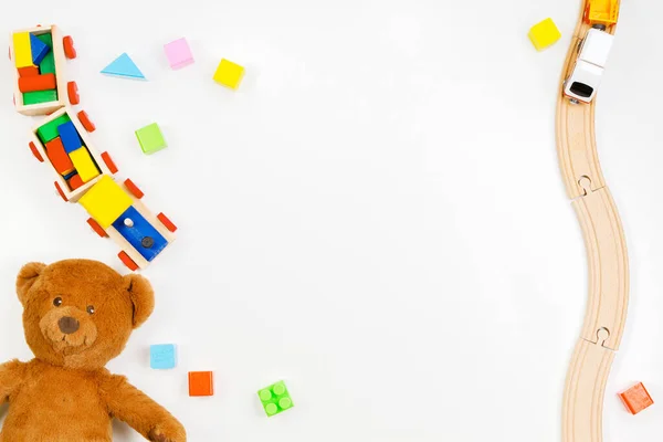 Baby kids leksaker bakgrund. Teddybjörn, trä tåg, färgglada tegelstenar på vitt bord — Stockfoto