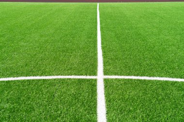 Yeşil yapay çim futbol sahası arka planında beyaz çizgiler var. Üst görünüm