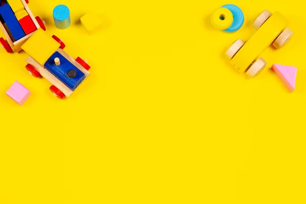 Baby kids toys background. Toy train, wooden car and colorful blocks on yellow background. Top view, flat lay — Stock Photo, Image