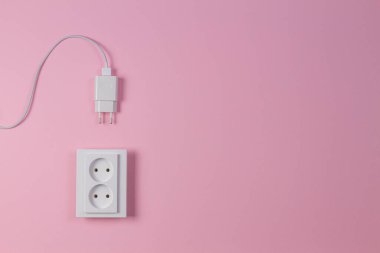 Beyaz elektrik prizi ve açık pembe arka planda elektrik prizi. Üst görünüm