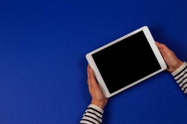 Lacivert arka planda dijital tablet bilgisayarı tutan kadın eller. Üst görünüm