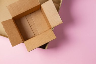 Açık pembe arka planda boş karton kutular. Üst görünüm